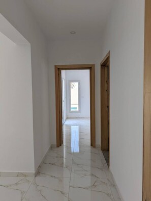 A hallway with a marble floor leading to a room with a window. - Escape to Villa Yasmina (Aghir)