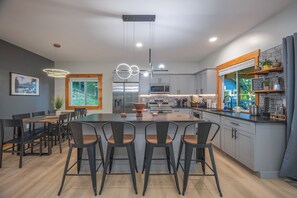 A modern kitchen with a central island, bar stools, and a dining table with chairs. - Sauna-Hot tub-Pool table-Pickleball-Treehouse with slide-Golf putting green (Blue Ridge)