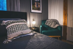 A hotel room with a bed, a nightstand, a lamp, a chair, and a wall-mounted picture. - Sauna-Hot tub-Pool table-Pickleball-Treehouse with slide-Golf putting green (Blue Ridge)
