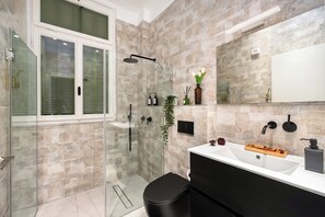 A modern bathroom with a glass-enclosed shower, a white sink, and a black vanity. - The Monti – Stylish 1‑Bedroom Apartment in Central Tel Aviv (Tel Aviv-Yafo)