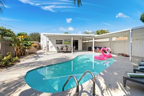 A backyard with a swimming pool, a covered patio area, and a seating arrangement. - West Palm Pool Home Sleeps 10 Game Room (West Palm Beach)