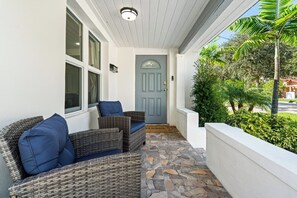 A covered porch with wicker furniture and a blue door. - West Palm Pool Home Sleeps 10 Game Room (West Palm Beach)