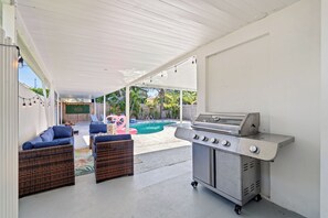 An outdoor patio with a barbecue grill, lounge chairs, and a pool. - West Palm Pool Home Sleeps 10 Game Room (West Palm Beach)