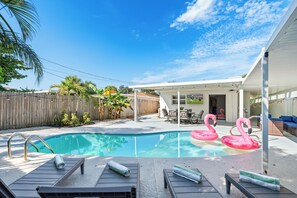 A backyard with a swimming pool, lounge chairs, and a covered patio area. - West Palm Pool Home Sleeps 10 Game Room (West Palm Beach)