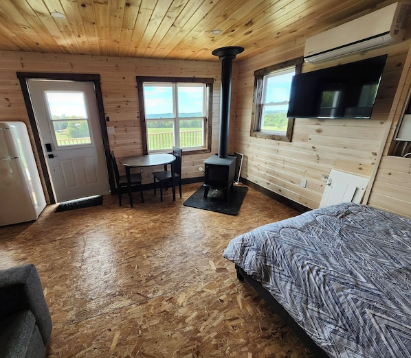 A room with a bed, a table with chairs, a stove, and a TV.