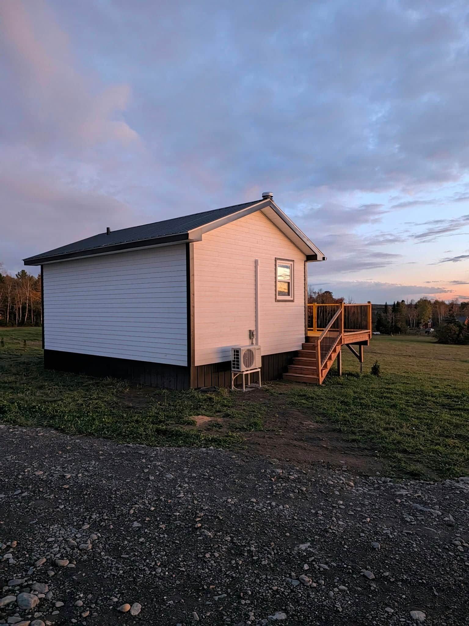 Ein eingeschossiges Gebäude mit einer kleinen Veranda und einer Treppe, die zu einer Terrasse führt.