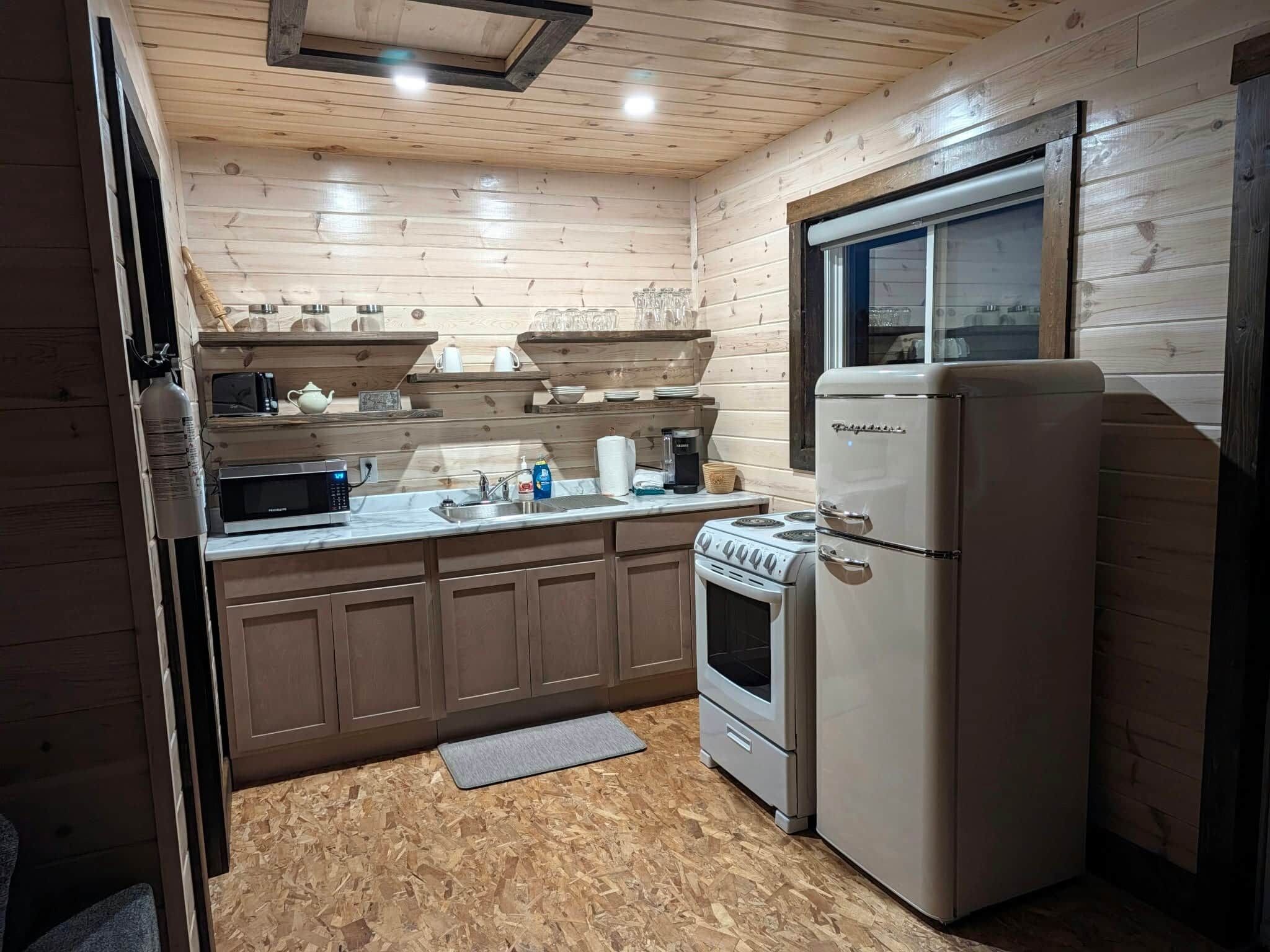 Eine kleine Küche mit Kühlschrank, Herd, Mikrowelle und Holzschränken.