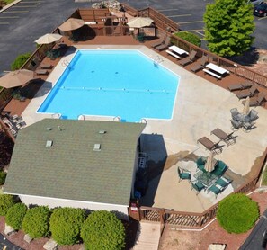 A rooftop swimming pool with lounge chairs and umbrellas, surrounded by a wooden deck and a small garden area. - SDC Ground Level Condo (Branson)