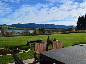 An outdoor seating area with a table and chairs, a stone wall, and a view of a lake and mountains. - Holiday Home With 3 Bedrooms (Lechbruck)