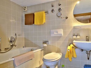 Ein Badezimmer mit Badewanne, Toilette, Waschbecken und Spiegel.
