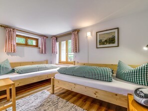 Ein Zimmer mit zwei Holzbetten, einem kleinen Tisch, einem Teppich und einem Gemälde an der Wand.