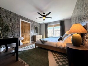 A bedroom with a bed, a desk, a chair, a lamp, a ceiling fan, and a window with curtains. - Eagle's Landing Chalet (Massanutten)
