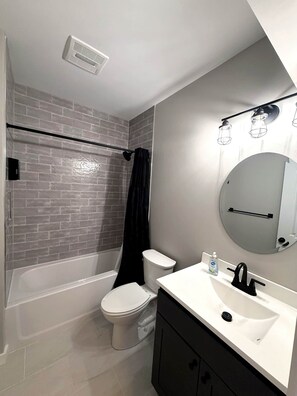 A bathroom with a shower, toilet, sink, and a mirror. - Eagle's Landing Chalet (Massanutten)