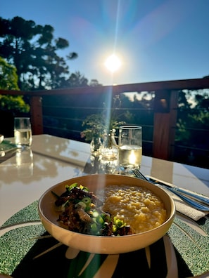 A table set outdoors with a meal, glasses, and a candle. - Treehouse in Campos do Jordão, a romantic retreat of good taste and tranquility. (Campos do Jordão)