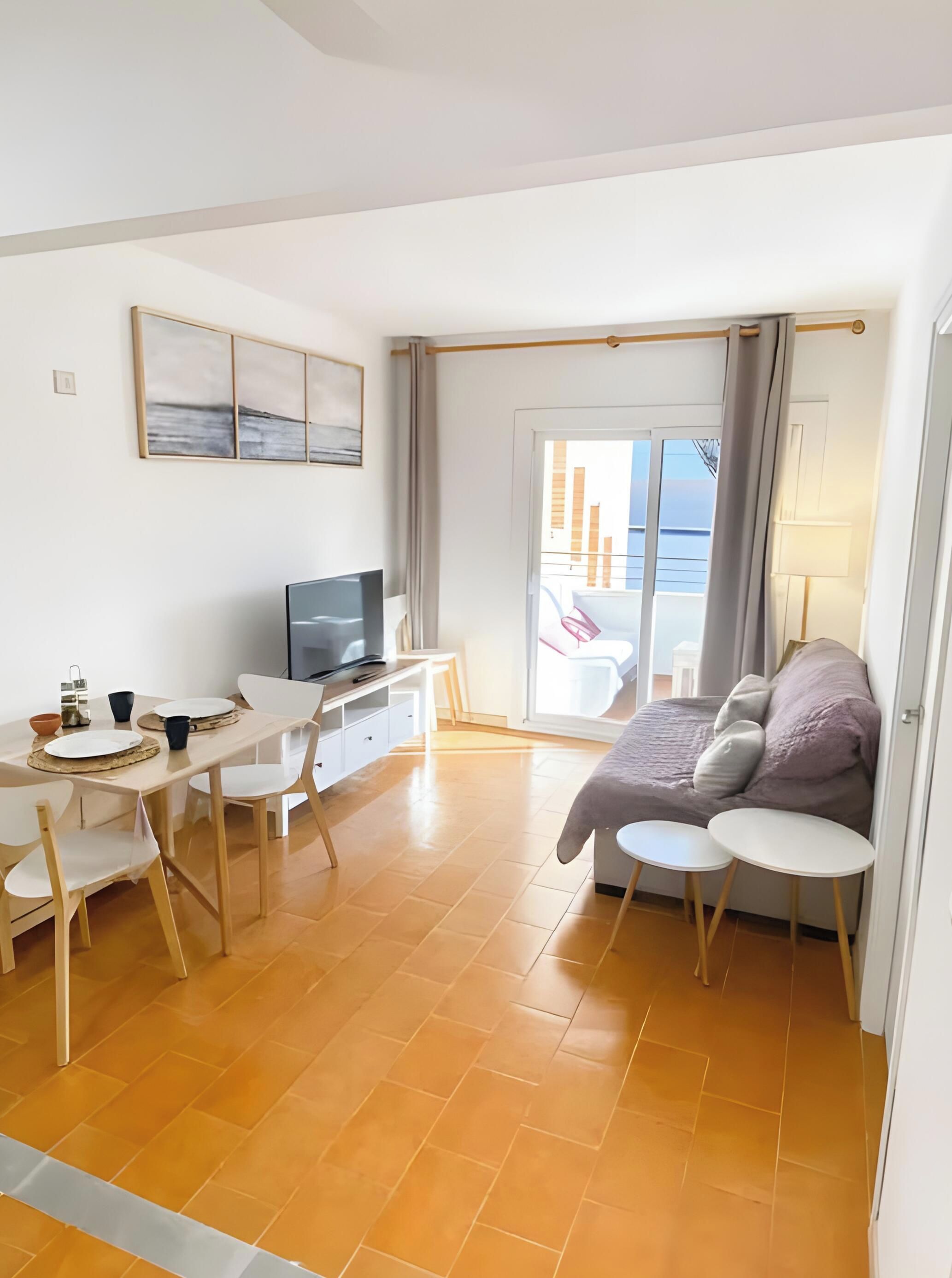 A modern room with a bed, a desk, a television, and a balcony with a view.