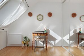 A room with a wooden floor, a table with a chair, a radiator, and wall decorations. - Kerlevenan House: A Peaceful Haven in the Heart of the Rhuys Peninsula (Sarzeau)