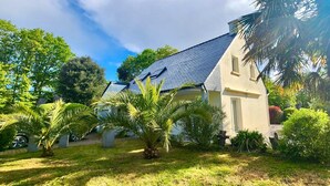 A house with a sloped roof, surrounded by a well-maintained garden with palm trees and shrubs. - Kerlevenan House: A Peaceful Haven in the Heart of the Rhuys Peninsula (Sarzeau)