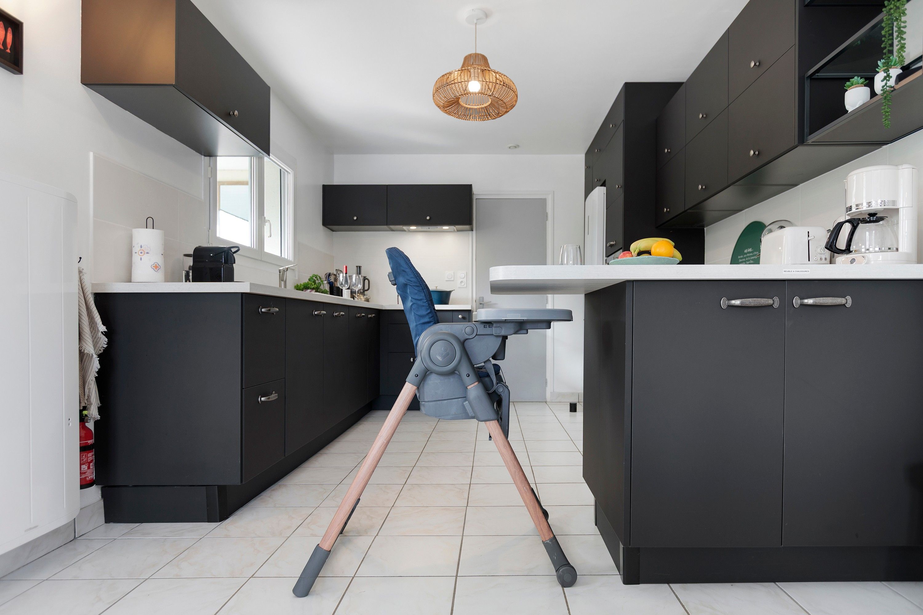 Et moderne køkken med sorte skabe, en hvid bordplade og en loftlampe.