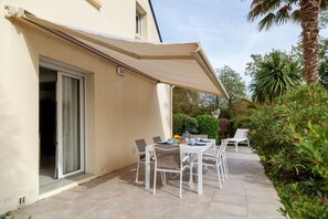 A patio with a table set for dining, surrounded by chairs, and a covered area with a canopy. - Kerlevenan House: A Peaceful Haven in the Heart of the Rhuys Peninsula (Sarzeau)
