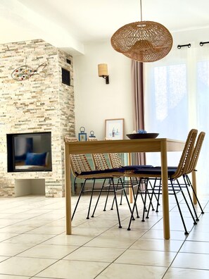 Een moderne woonkamer met een stenen muur, een flatscreen televisie, een eettafel met stoelen en een hanglamp.