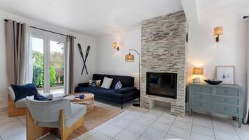 A living room with a stone fireplace, a sofa, a coffee table, and a TV.
