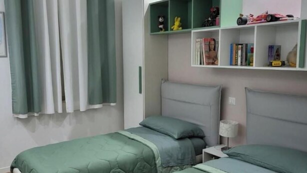 Ein Schlafzimmer mit zwei Betten, einem Bücherregal und einem Vorhang.