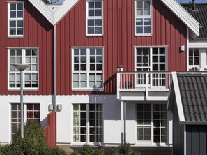Ein rotes Gebäude mit weißem Zierrat, zahlreichen Fenstern und einem Balkon mit Geländern.