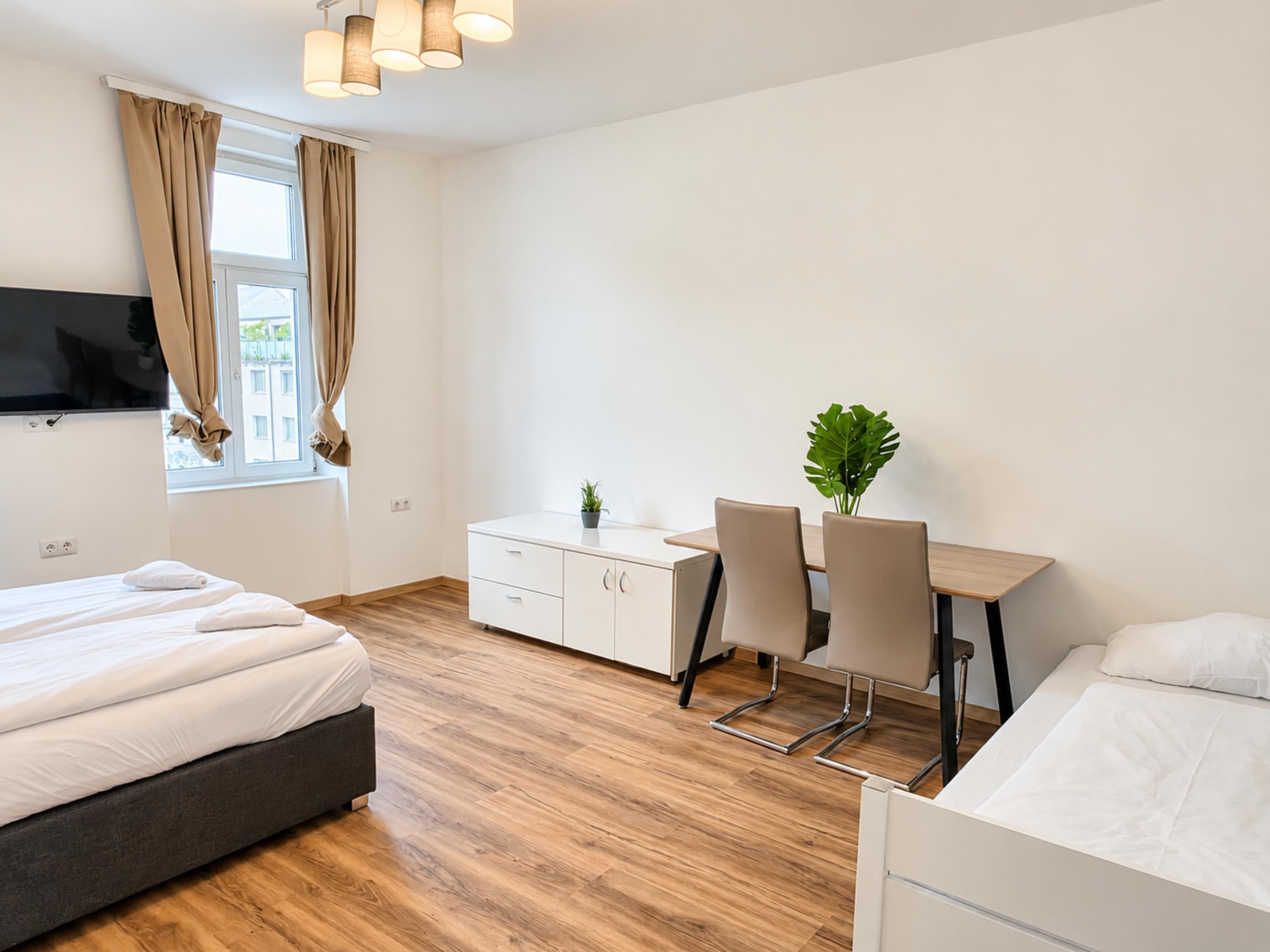 A modern hotel room with a bed, a desk, and a TV.