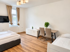 A modern hotel room with a bed, a desk, and a TV. - Your Vienna Hideaway 1BR Apartment near Wiener Stadthalle (Vienna)