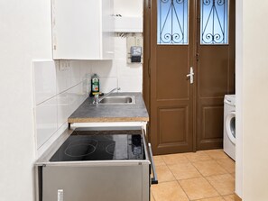 A compact kitchen with a built-in stove, a sink, and a washing machine. - Your Vienna Hideaway 1BR Apartment near Wiener Stadthalle (Vienna)