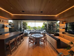 A modern kitchen with a central island, bar seating, and a large window overlooking greenery. - Aura 41 Un refugio sobre Reforma (Ciudad de México)