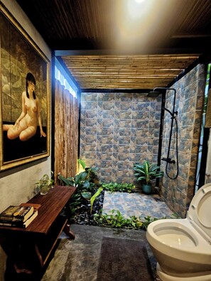 Casa de banho com chuveiro, sanita e banco.