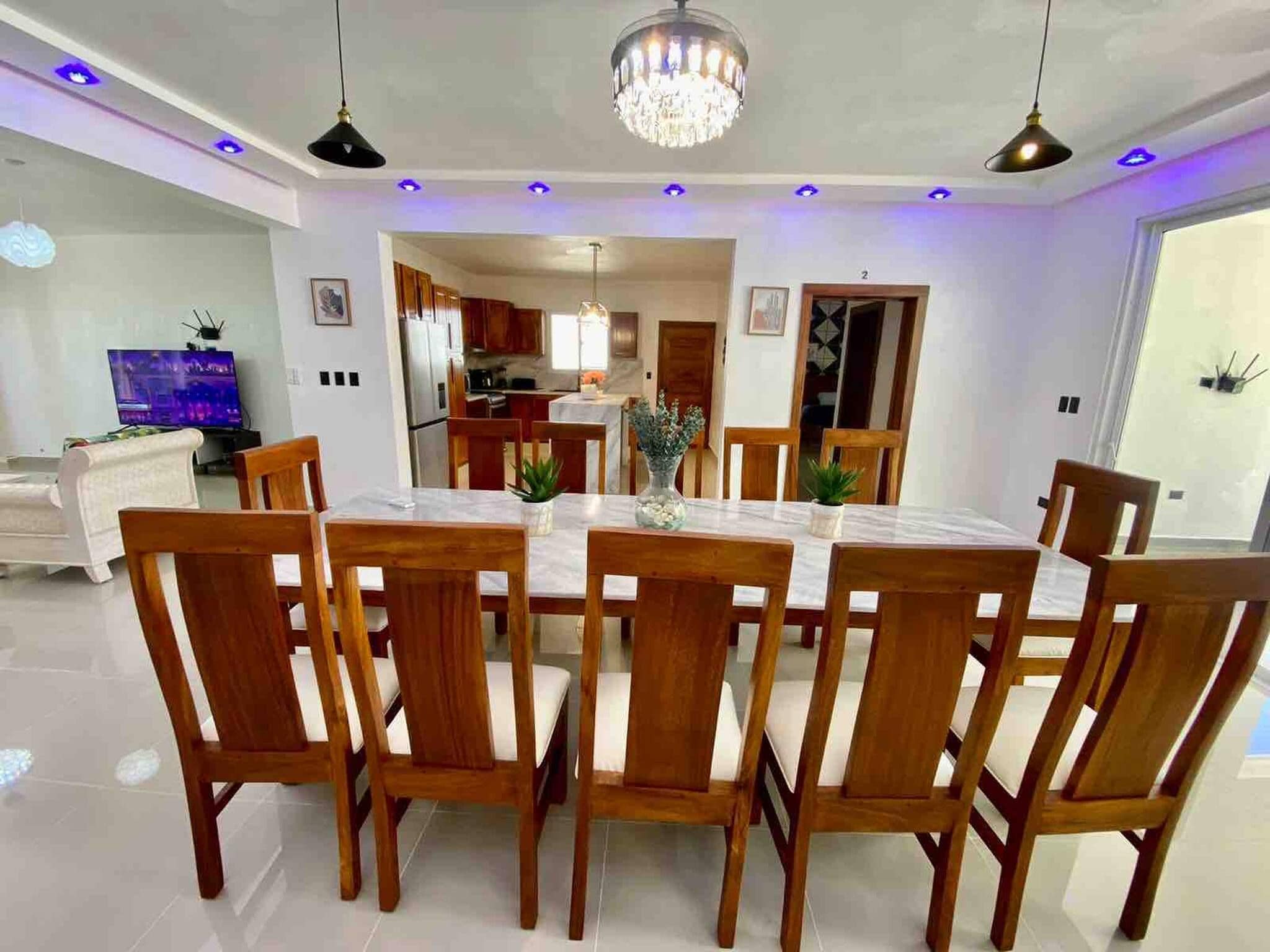 Un comedor con una mesa redonda, sillas de madera y una araña.