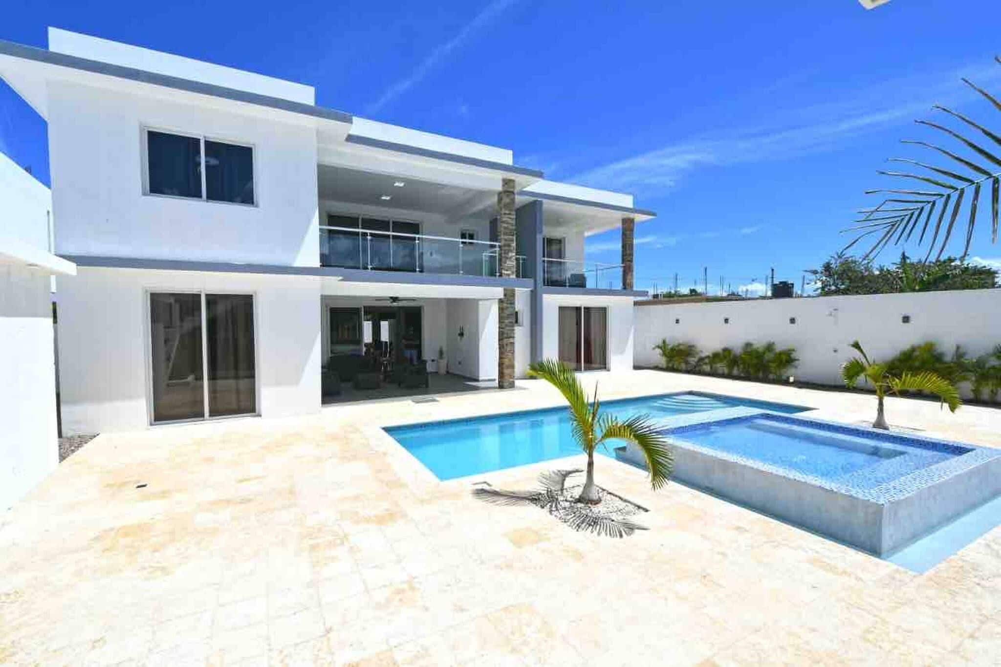 A modern two-story house with a swimming pool, a covered patio, and a view of the sky.