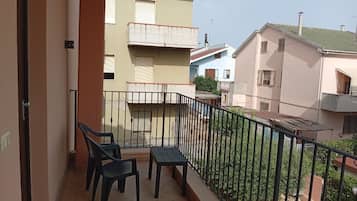 Een balkon met twee stoelen en een tafel, met uitzicht op omliggende gebouwen.
