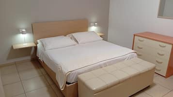 Een slaapkamer met een bed, nachtkastjes, een kaptafel en een bankje.
