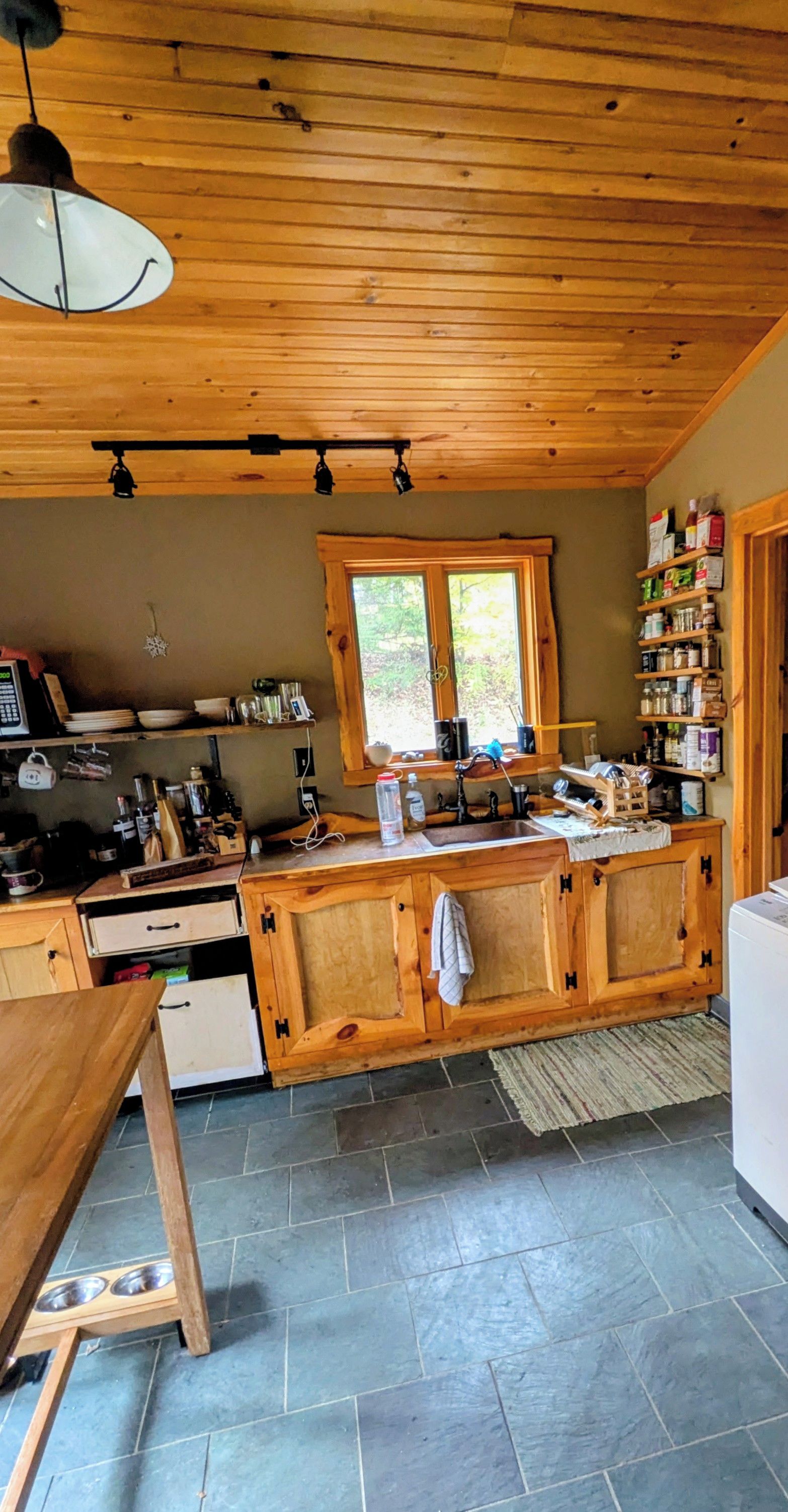 A kitchen with wooden cabinets, a window, and a tiled floor.