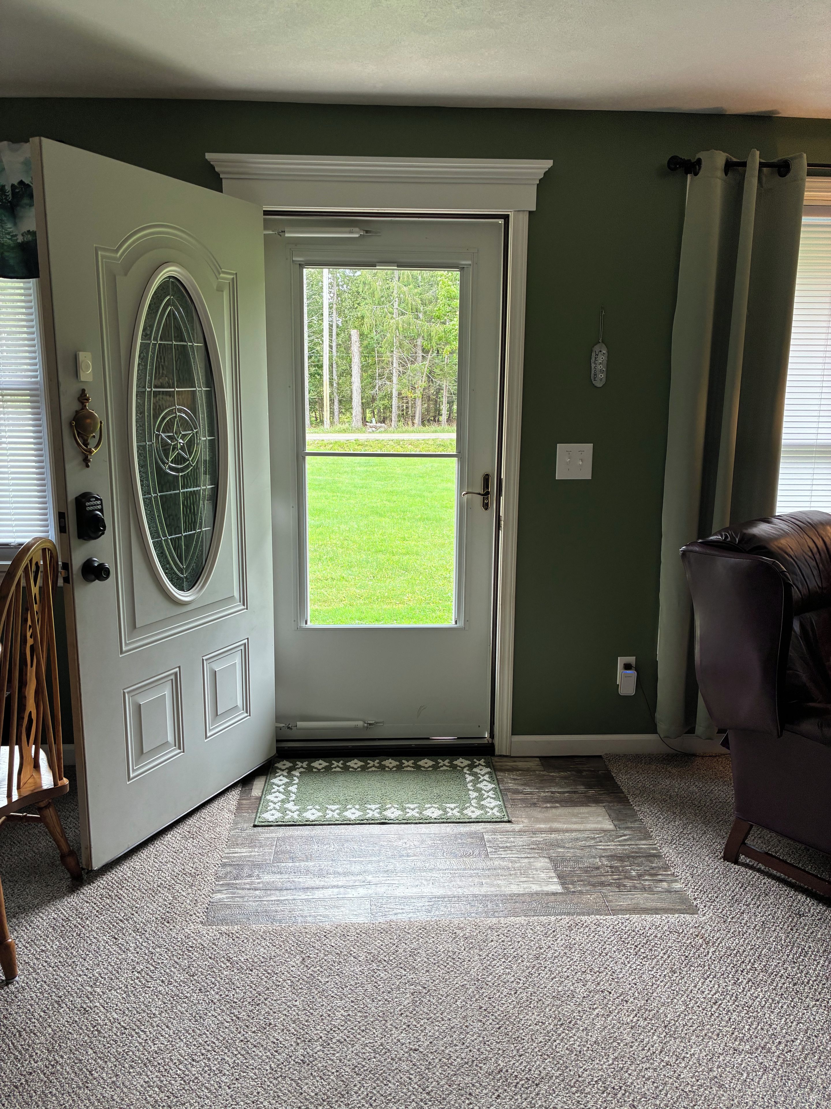 A room with a door leading to a lawn, a coat rack, and a power outlet on the wall.