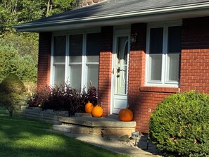 A brick house with a front porch, a door, and a window. - Peaceful 15-Acre Retreat Near Cook Forest The Forest Glenn—Perfect for Families (Lucinda)