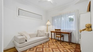 A room with a sofa, a wooden chair, a lamp, a teddy bear, and a patterned rug. - Serenity Escape - Private, Pet-Friendly Home on the Broadwater (Bilambil Heights)