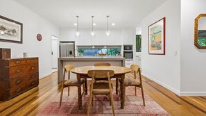 A modern kitchen with white cabinets, a central island, and pendant lighting. - Serenity Escape - Private, Pet-Friendly Home on the Broadwater (Bilambil Heights)