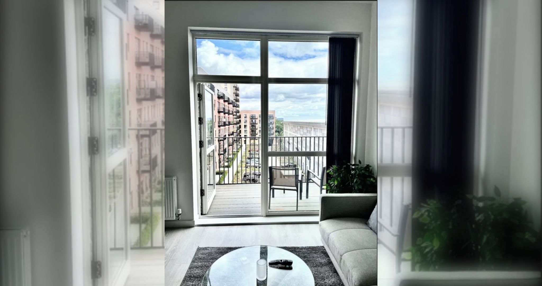 Ein modernes Wohnzimmer mit einer großen Glasschiebetür, die auf einen Balkon führt.
