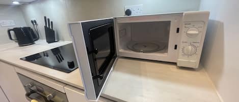 Une cuisine équipée d’un four à micro-ondes, d’une bouilloire et d’un bloc à couteaux.