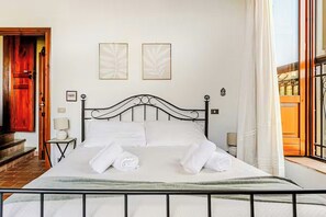 A neatly made bed with white linens and towels, a black metal headboard, and two framed artworks on the wall. - Family home in the UNESCO Valley of the Temples (Agrigento)