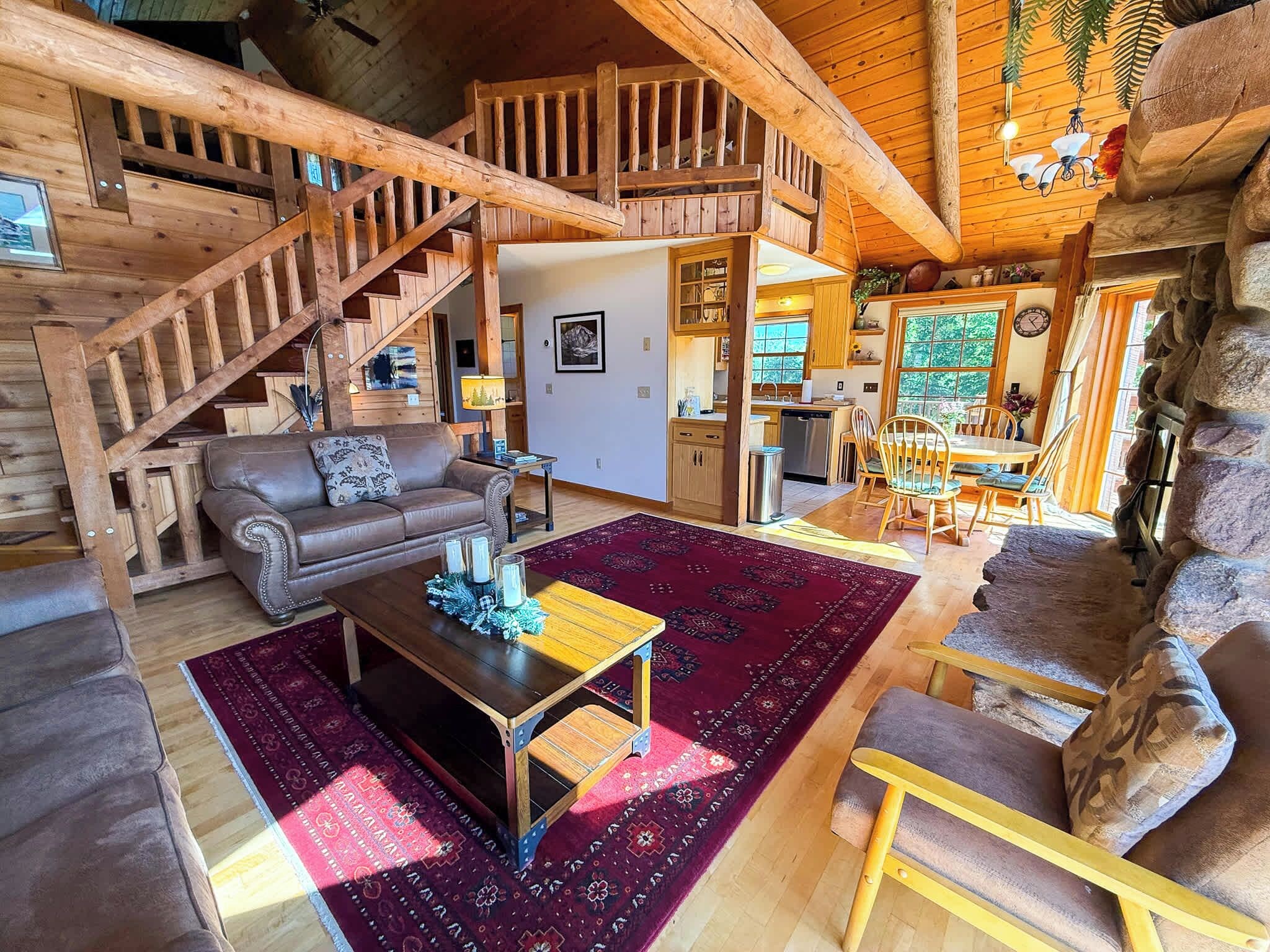 A spacious living area with a wooden staircase, a dining table, and a kitchen in the background.
