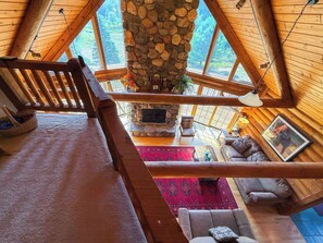 A spacious loft bedroom with a stone fireplace, a wooden ceiling, and a view of the outdoors. - Nellie's Lodge-Outdoor Sauna, close to X-C Ski Trails (Ironwood)