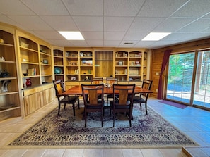 A dining area with a wooden table and chairs, surrounded by bookshelves filled with books and decorative items. - Nellie's Lodge-Outdoor Sauna, close to X-C Ski Trails (Ironwood)