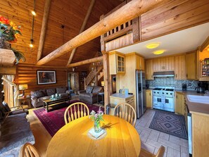 Ein rustikales Blockhaus-Interieur mit Essbereich, Küche und Wohnzimmer.