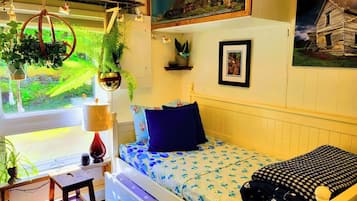 Une petite pièce agréable et confortable, avec un lit, un bureau et une fenêtre donnant sur un jardin.