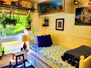 A small, cozy room with a bed, a desk, and a window overlooking a garden.